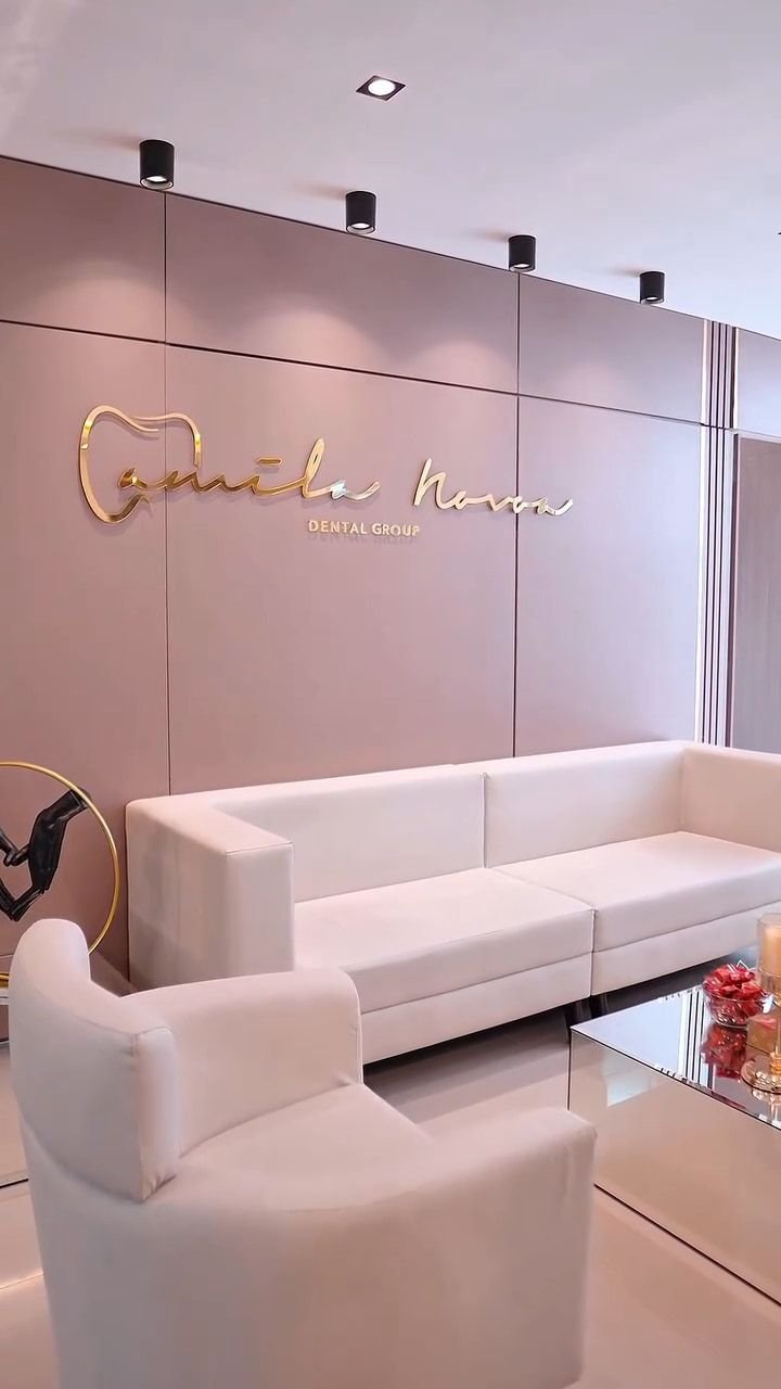 Sala de espera con sofás blancos y el logo dorado