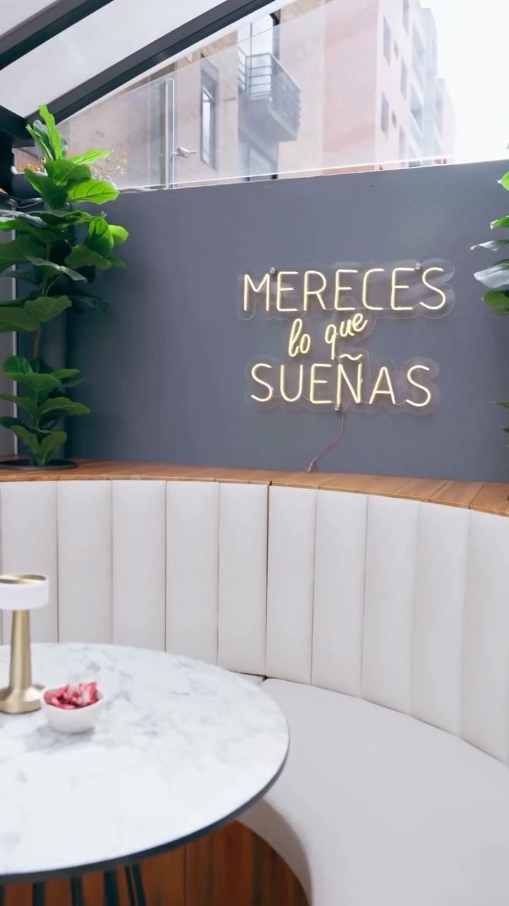 Letrero de neón Mereces lo que sueñas sobre un sofá curvo blanco