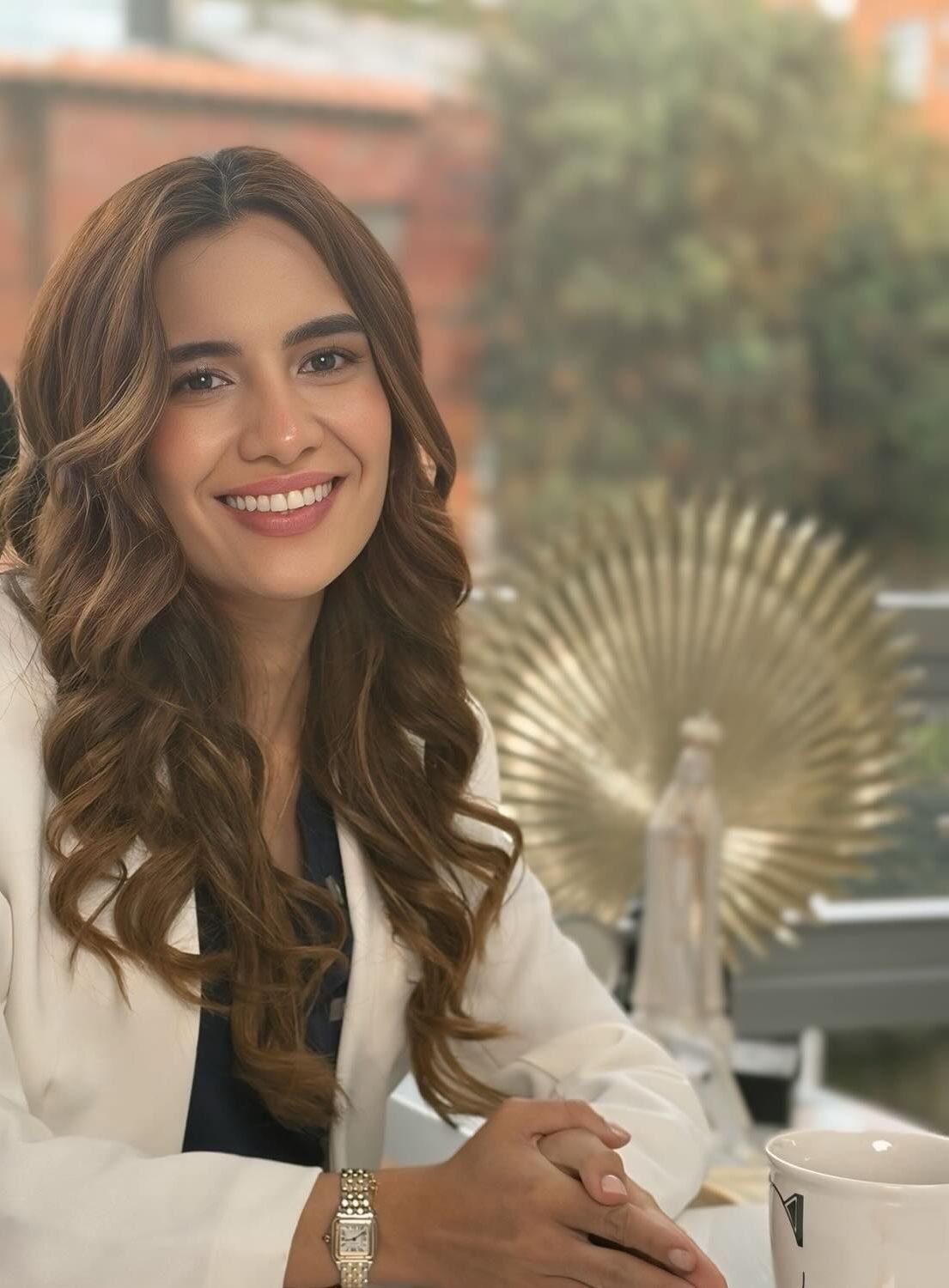 La Dra. Camila Novoa sonriendo en su consultorio, con blazer blanco